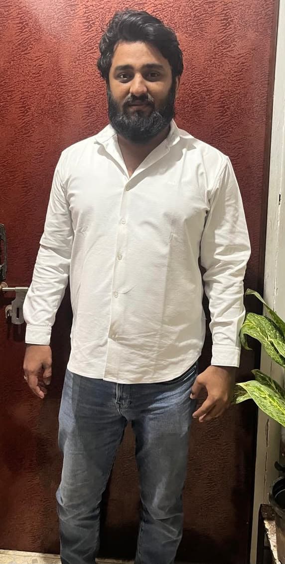 Before: client in a white shirt and jeans, standing against a red wall.