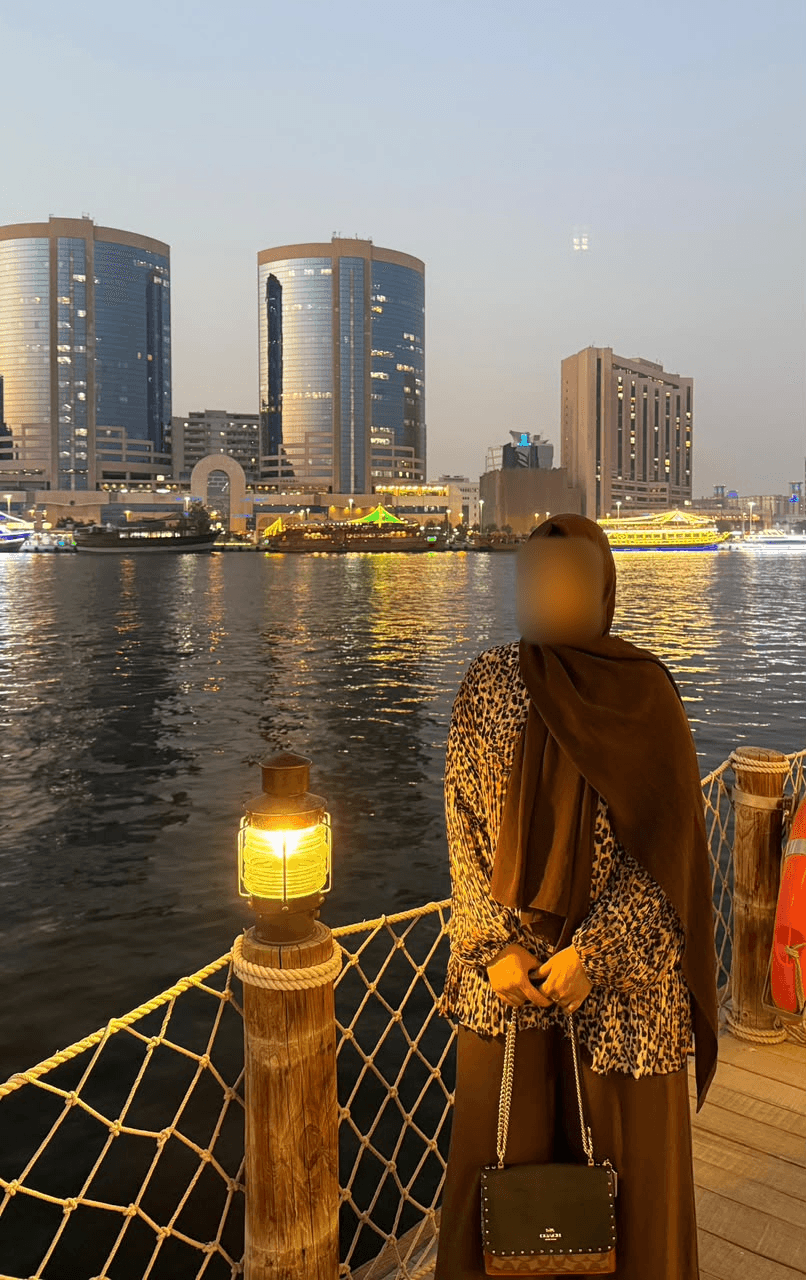 Before: client standing by the waterfront in a patterned outfit, with her face blurred for privacy.